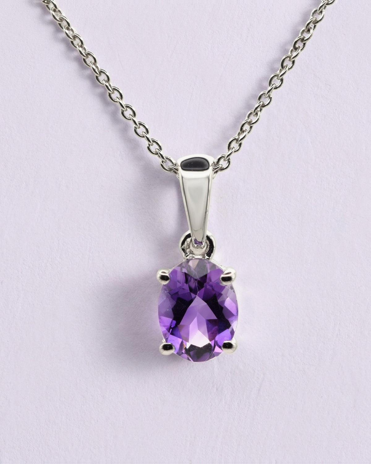 Verde Halskette aus 925 Sterlingsilber mit Amethyst, oval 6 x 8 mm, vor einer lavendelfarbenen Wand